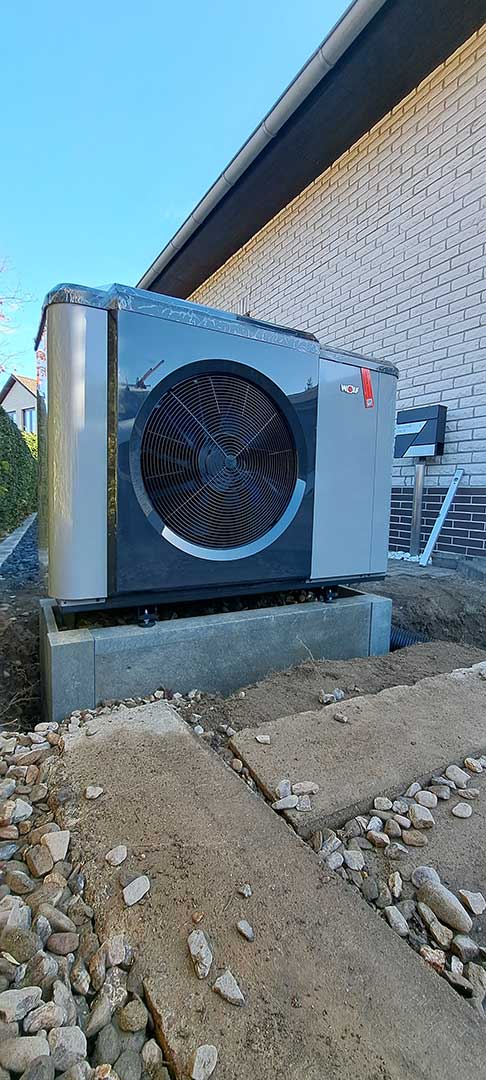 Außeneinheit einer Wärmepumpe im Garten neben Haus installiert