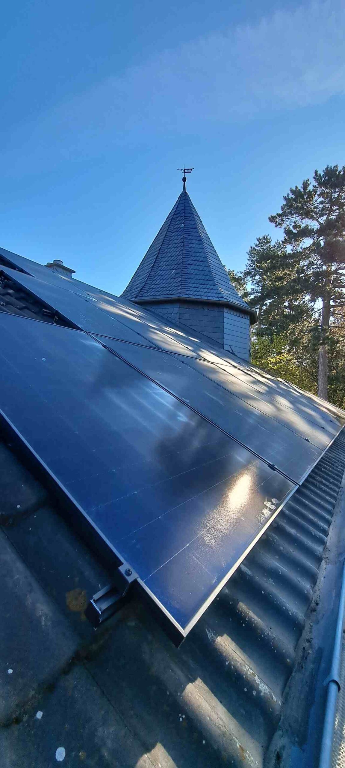 Photovoltaikmodule auf Steildach mit Kirchturm im Hintergrund